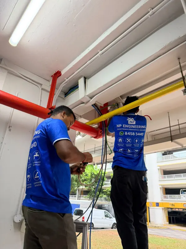 NP Engineering technicians working on wiring below ceiling pipes at Blk 233 Lorong 8 Toa Payoh